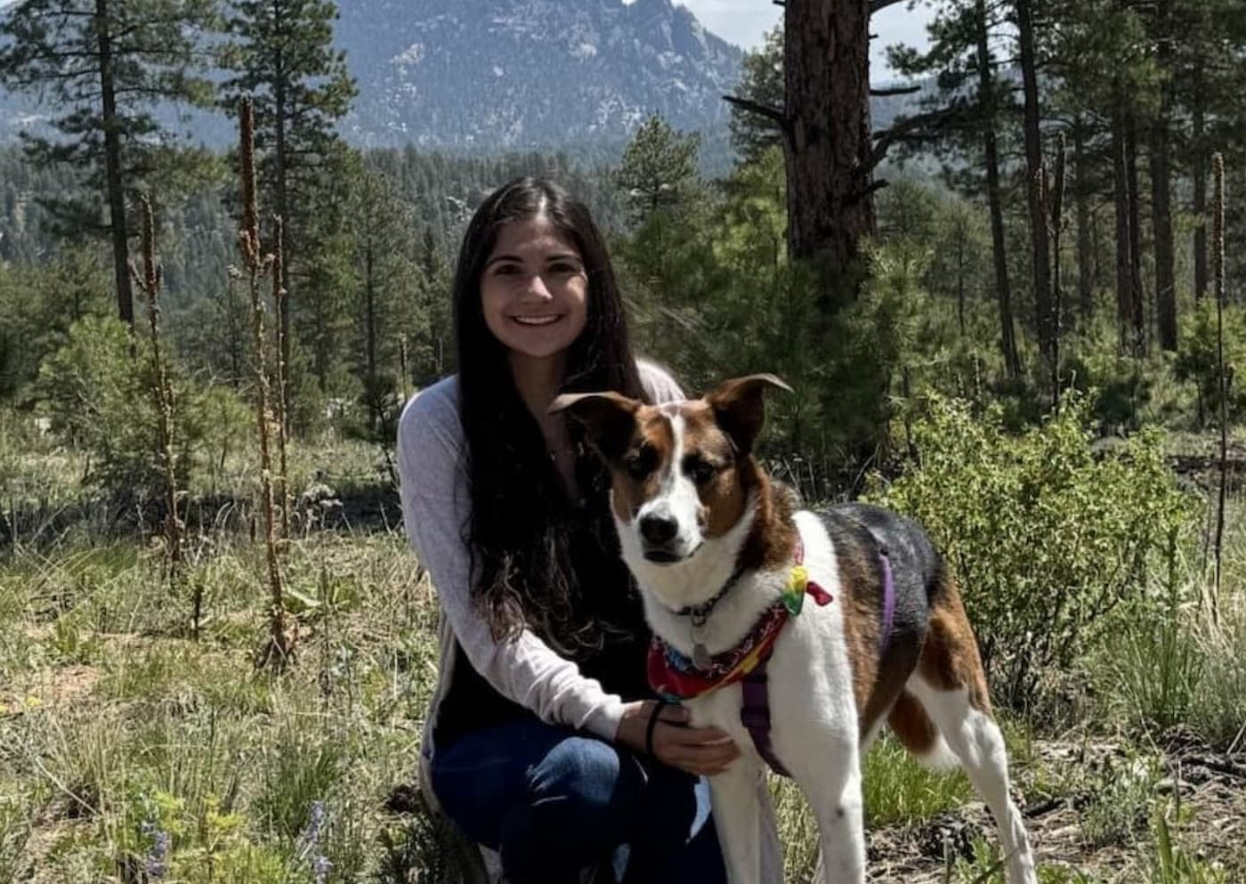 Veterinary extern kneeling with a dog on a mountain trail
