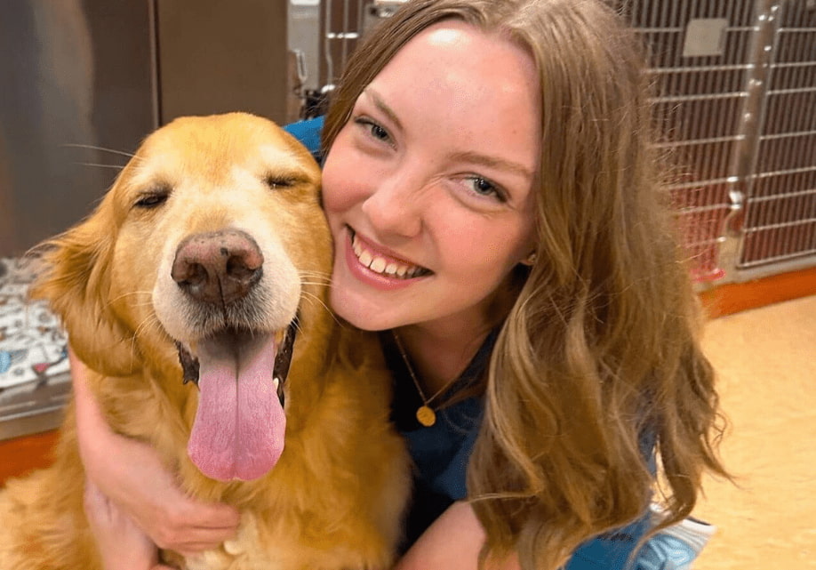 Veterinary extern smiling with a golden retriever